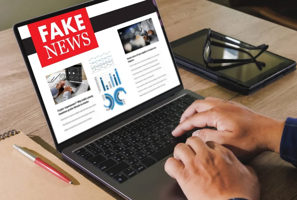 Person typing on laptop showing fake news article
